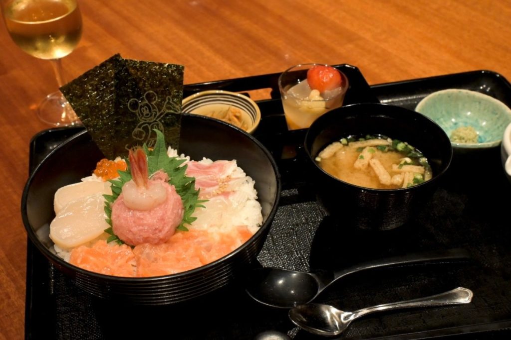 ネギトロやホタテ、サーモンなど色とりどりの具材が美しく盛られた海鮮ちらし丼。ミッキーの絵があしらわれた海苔がアクセント。