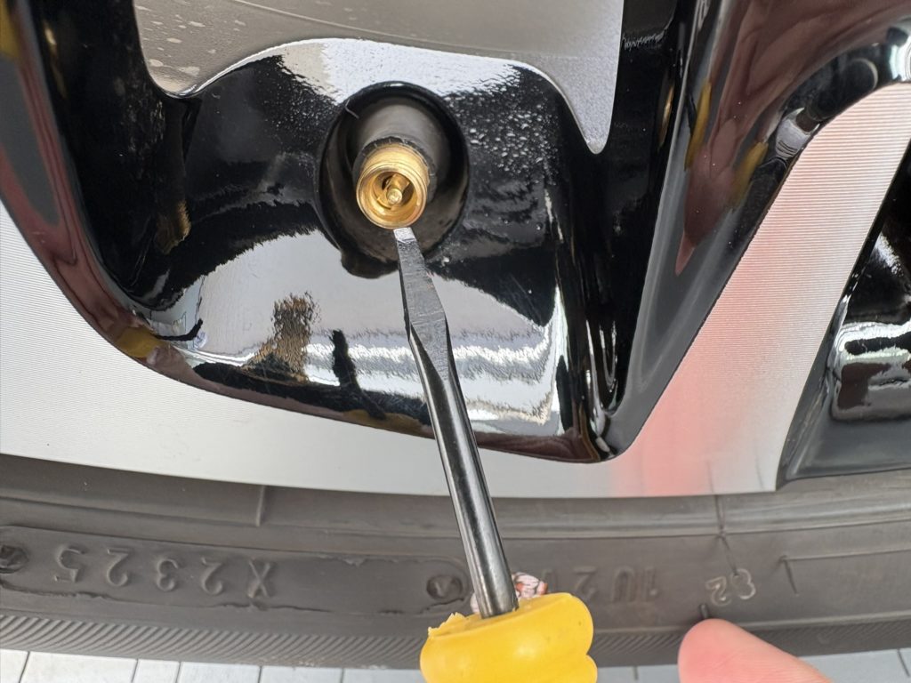 マイナスドライバーでバルブの芯を押してタイヤの空気を抜いている様子